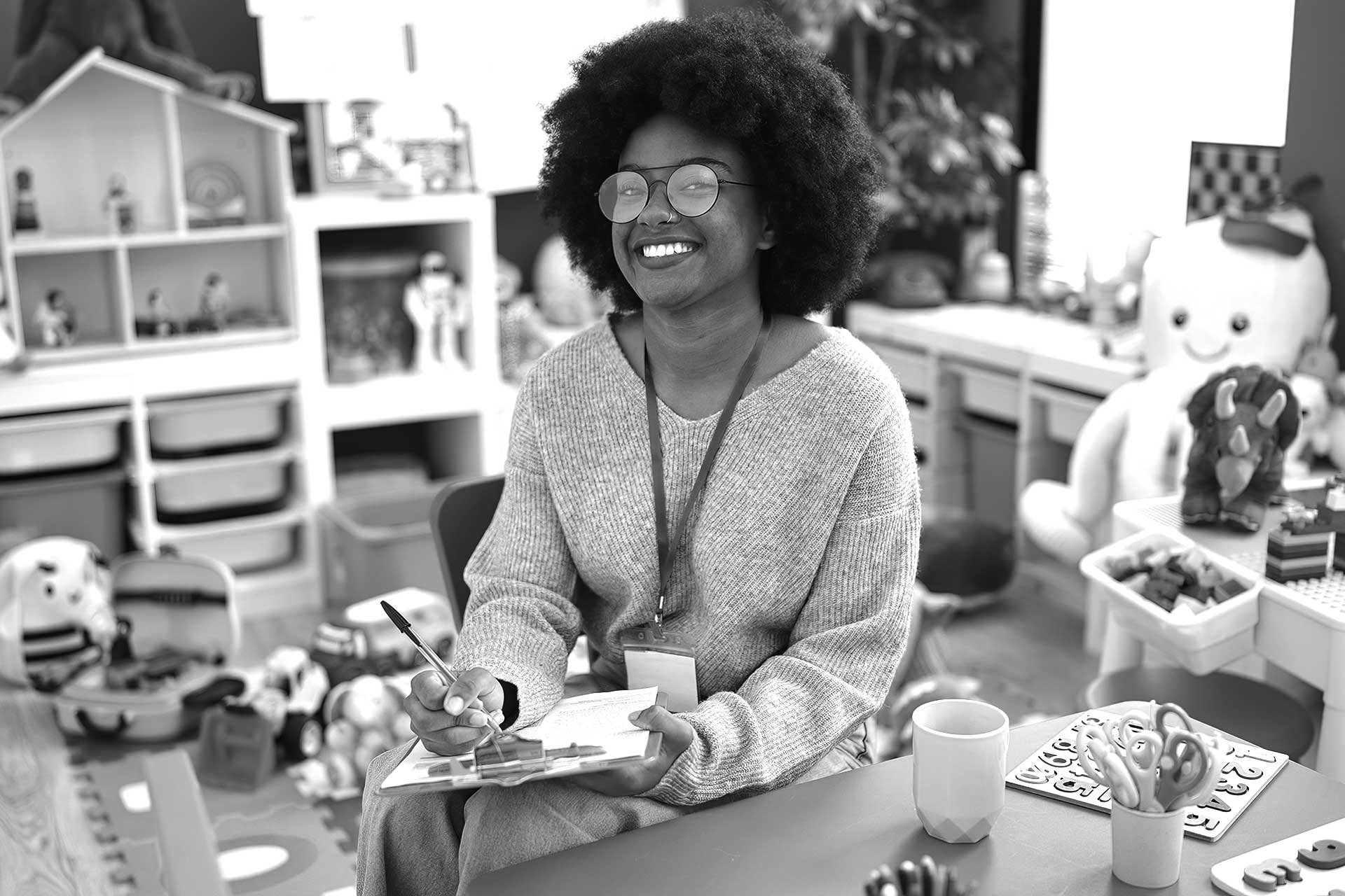 smiling teacher with glasses in a preschool classroom