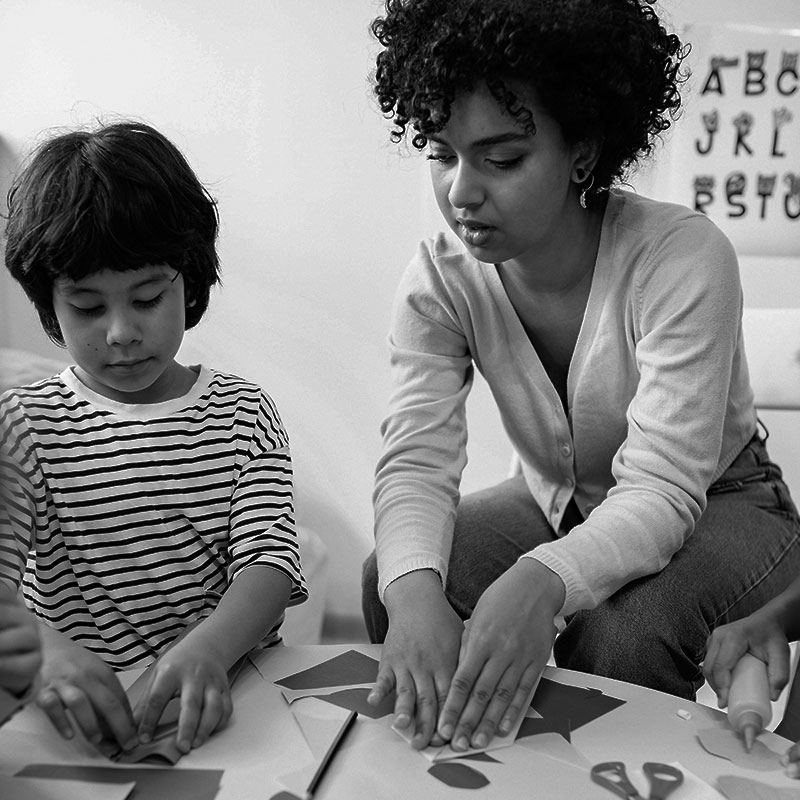 young teacher with a child cutting paper